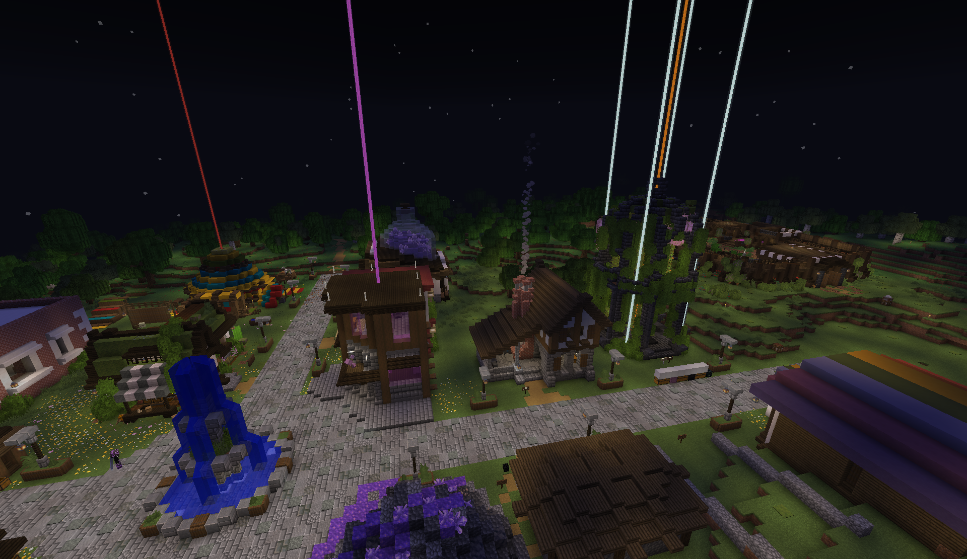 Shopping district at night with a central fountain and colorful beacon beams