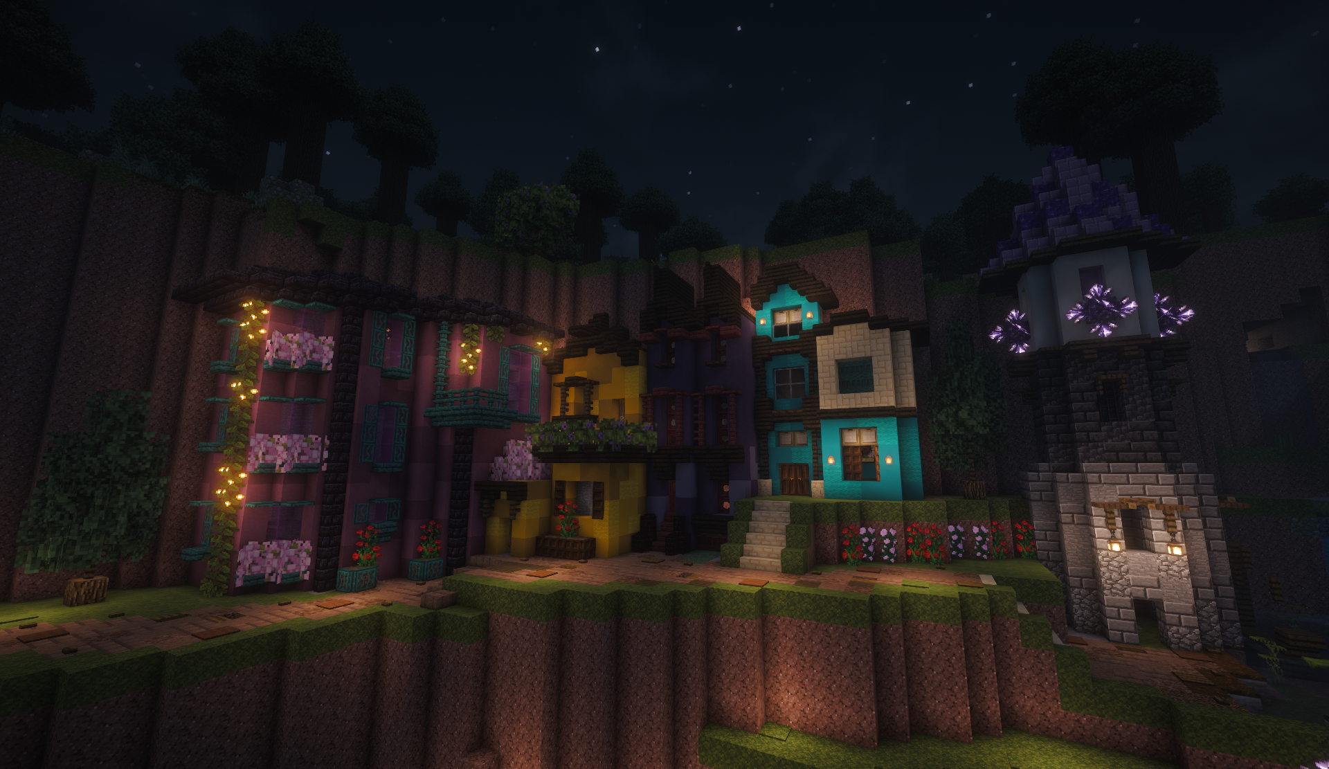 Colorful cliffside village at night with pink, yellow, and teal houses