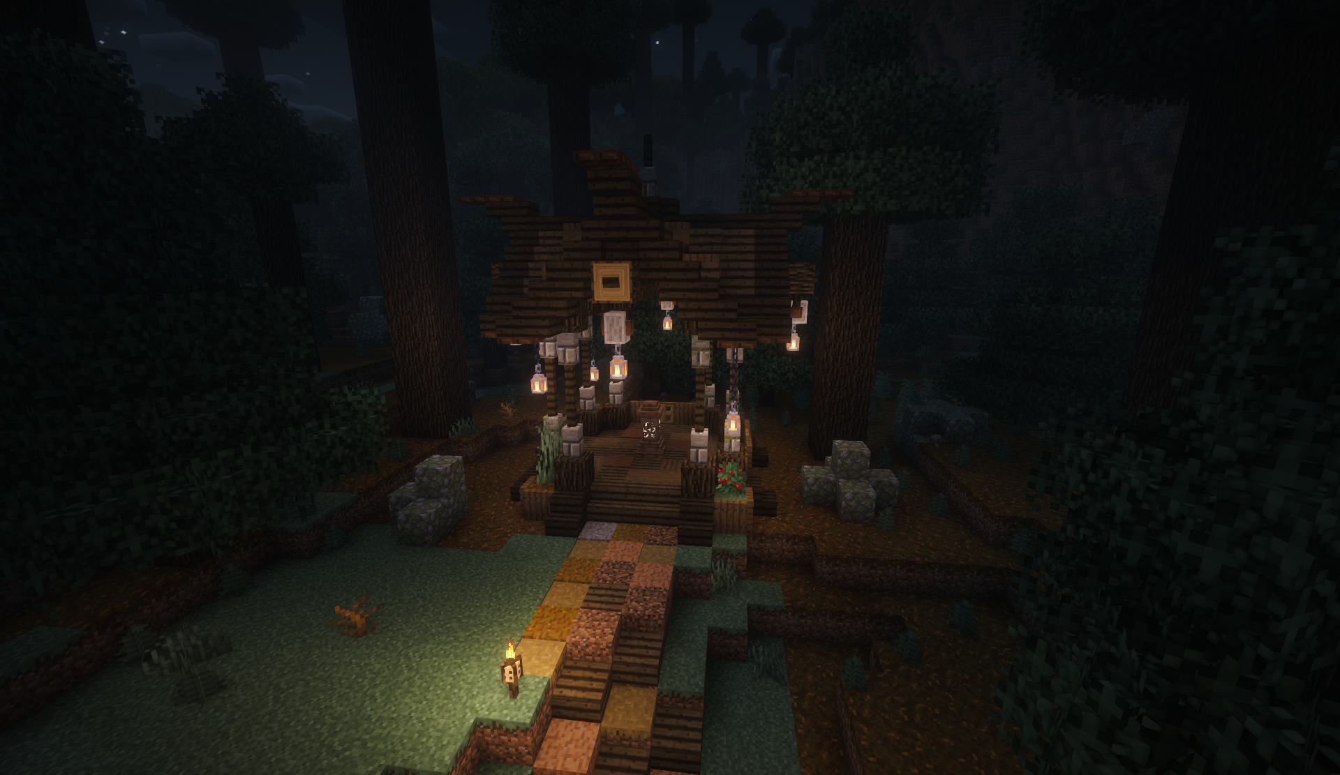 Lantern-lit wooden forest shrine among tall trees at night